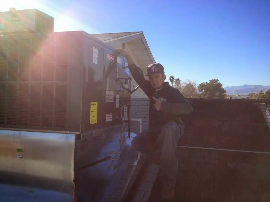 HVAC technician performing Air Duct Cleaning on a rooftop unit in Encinitas